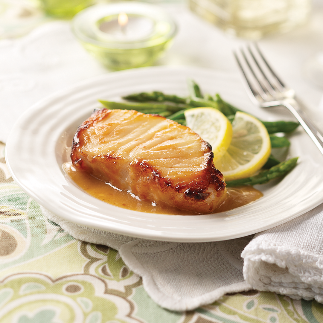 one miso sea bass filet on a plate with lemon and green beans.