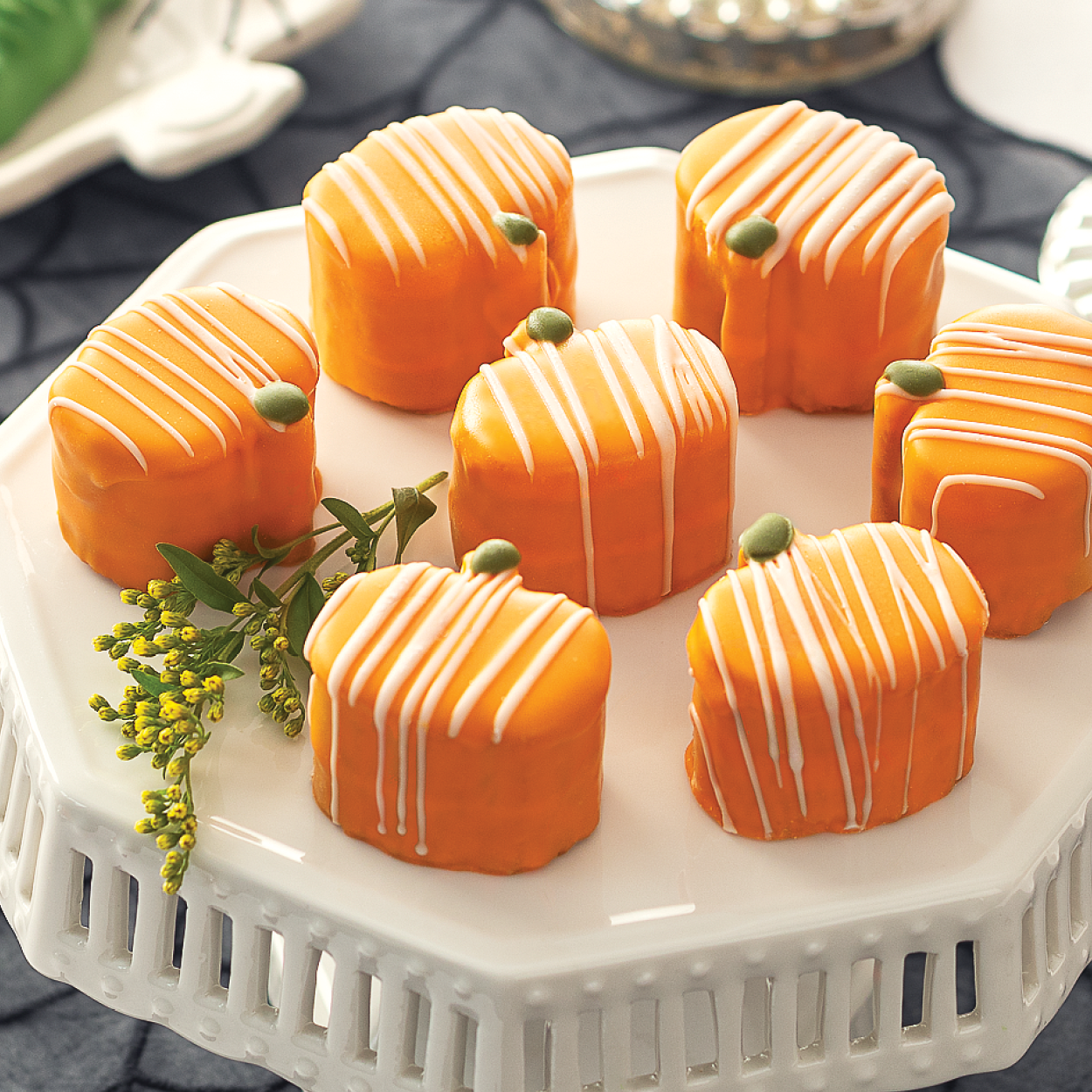 Orange Pumpkin Tea Cakes with white lined frosting on a tray