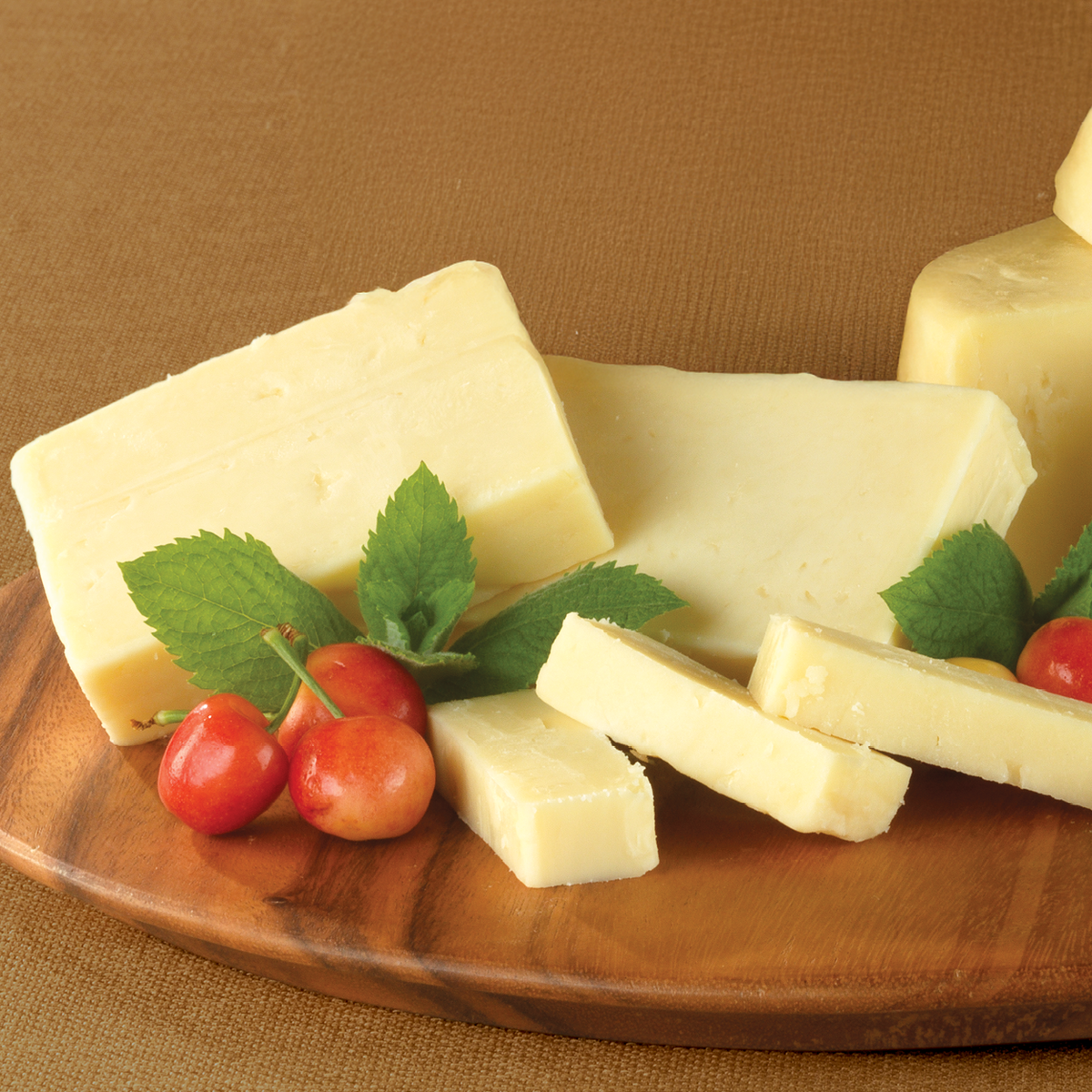 Aged Vermont Cheddar Cheese cut up on a wooden tray.
