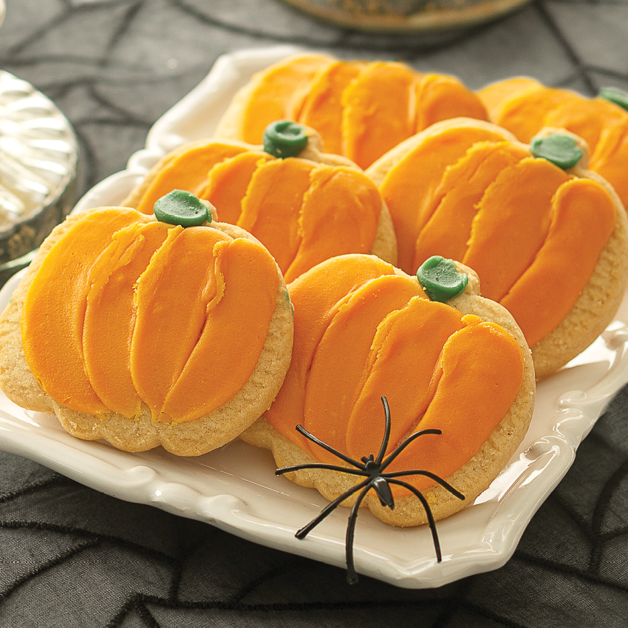 Orange Pumpkin Frosted Cookies on a tray with Halloween decor.