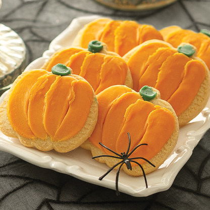 Orange Pumpkin Frosted Cookies on a tray with Halloween decor.