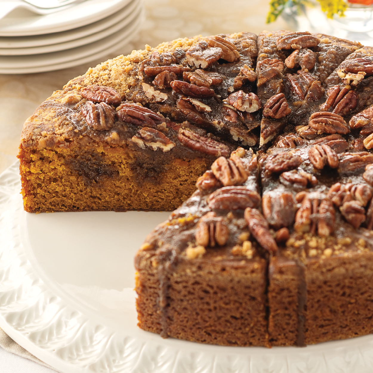 An up close photo of the Praline Pumpkin Cake topped with walnuts on a while display plate.