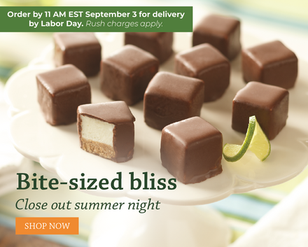Chocolate-covered bite-sized treats arranged on a white pedestal plate, with one piece cut open to show a cream filling and a biscuit-like base. A lime wedge sits on the plate. Order by 11am on September 3 for delivery by Labor Day.