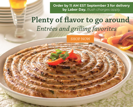 Grilled spiral sausage on a white plate with red pepper and parsley garnish, set on a table. Order by 11am on September 3 for delivery by Labor Day.