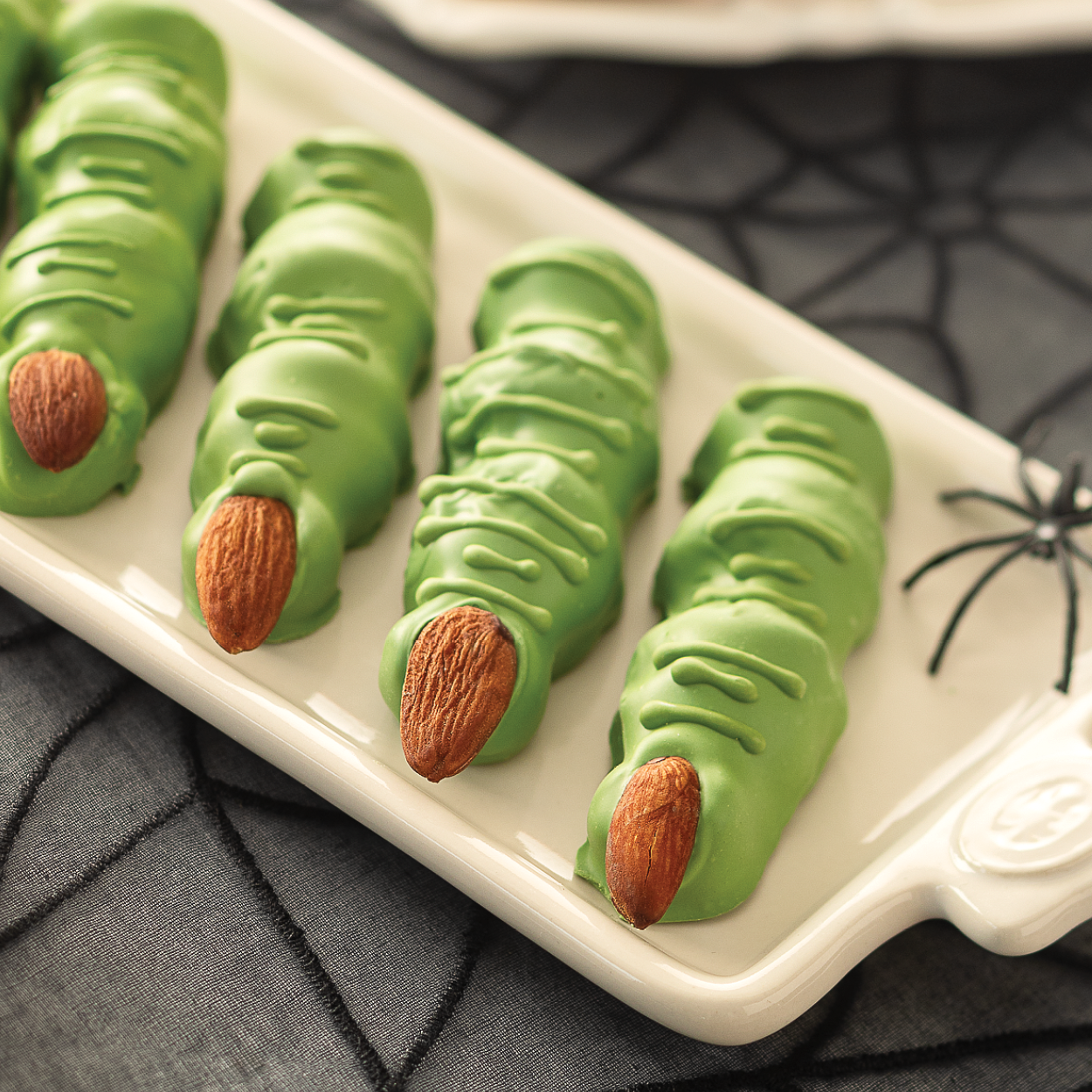 Green Witches Fingers Halloween candy on a tray with Halloween decor.