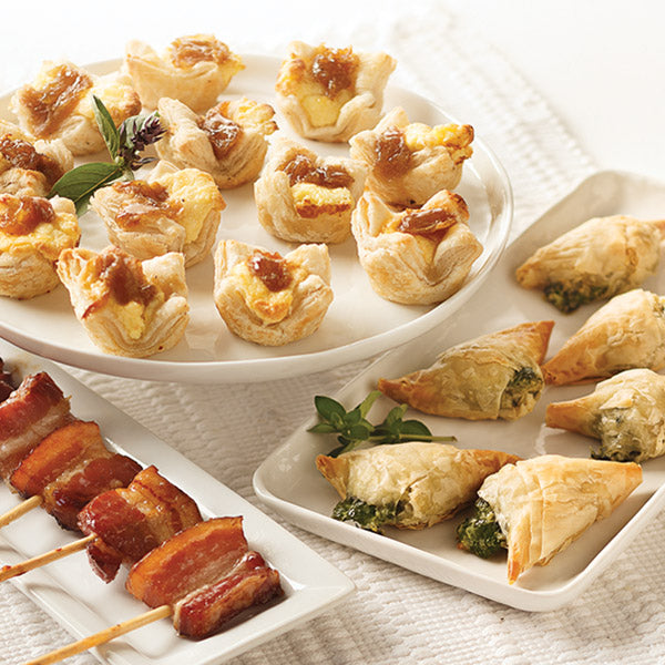 Top Rated Appetizer Sampler, featuring Vanilla-Bourbon Bacon Lollipops, Caramelized Onion & Feta Pastry Blossoms, and Spanakopita.